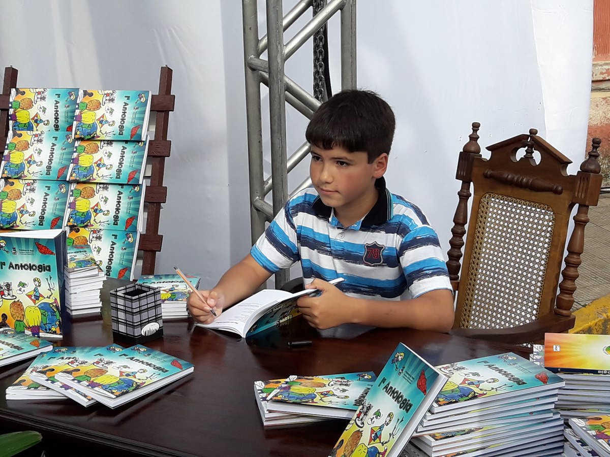 Aluno autografa exemplar da Antologia durante sessão de autógrafos.