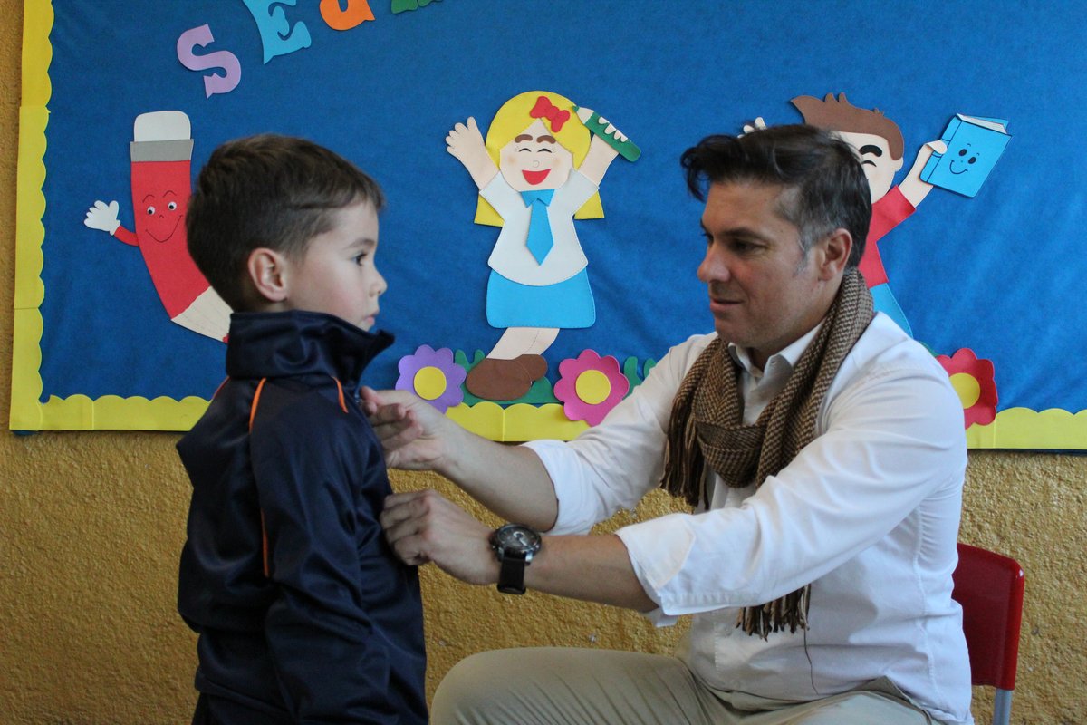 Divaldo Lara ajusta o novo uniforme em aluno da Educação Infantil.
