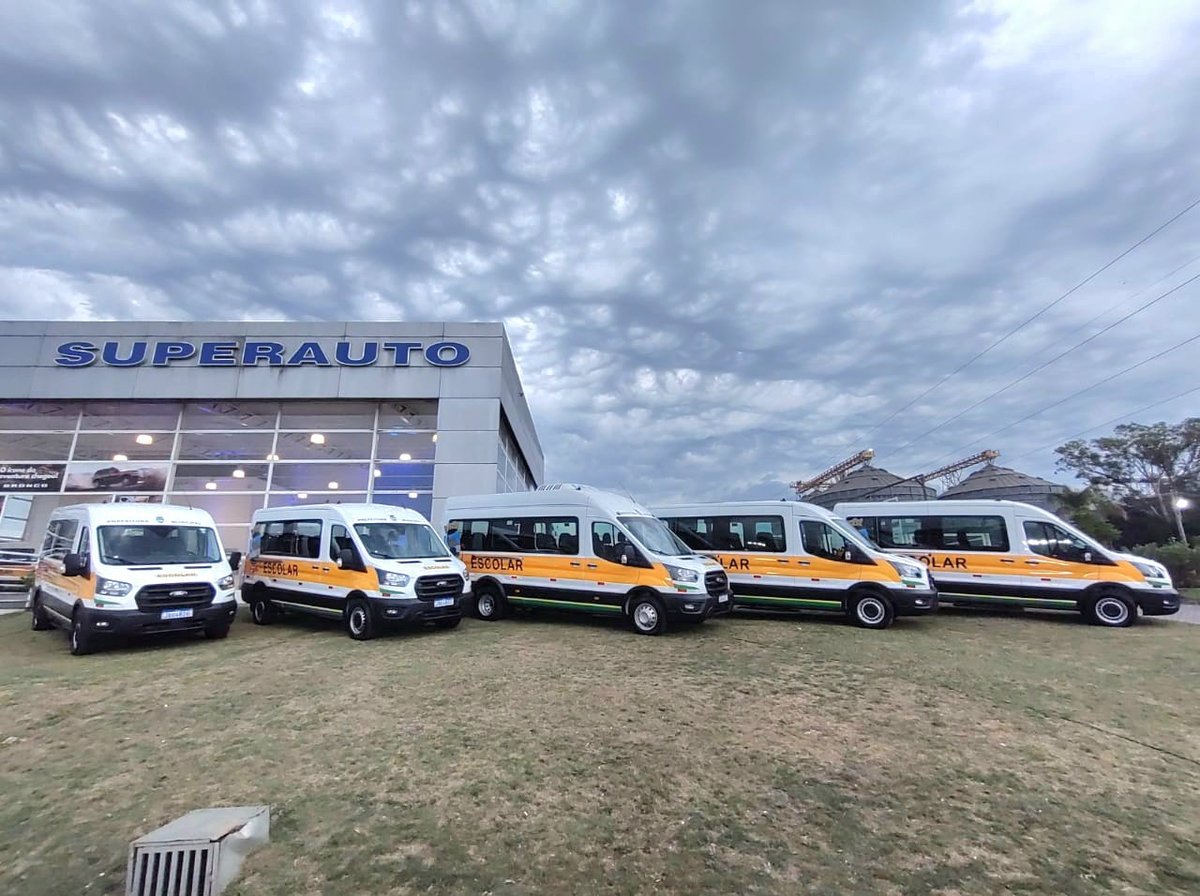 Vans escolares alinhadas em frente à concessionária Superauto.